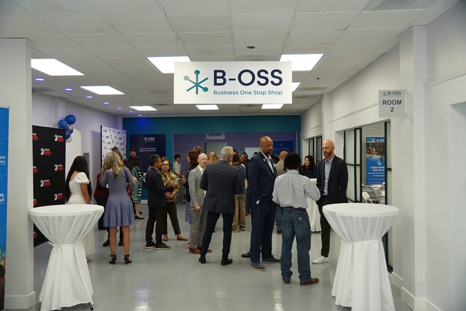 Guests gather under the B-OSS sign at the ribbon cutting